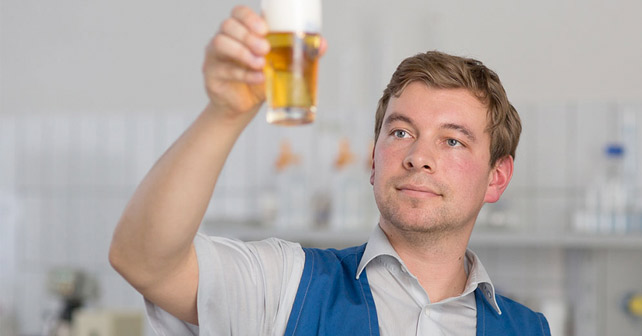 OeTTINGER-Mitarbeiter begutachtet ein Bier