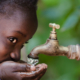 Mädchen trinkt Wasser aus Wasserhahn