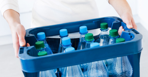 hände einer frau mit einem kasten mineralwasser