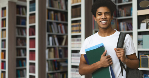 male student posing in campus library, empty space