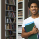 male student posing in campus library, empty space