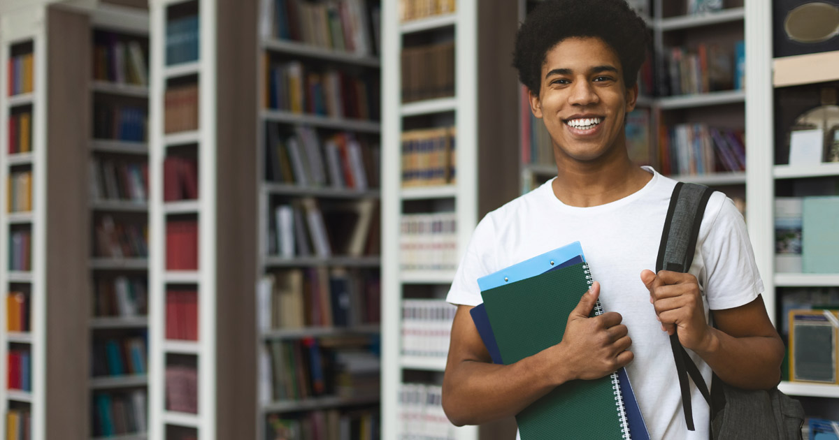 male student posing in campus library, empty space