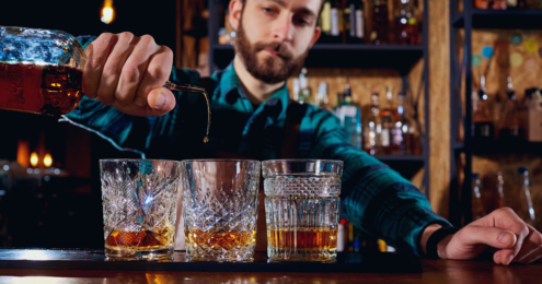 barman pours alcohol into a glass