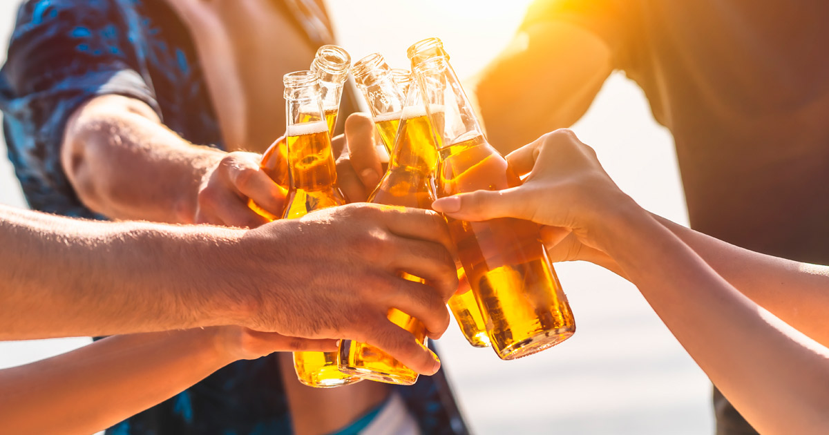 The hands holding bottles with beer and making cheers