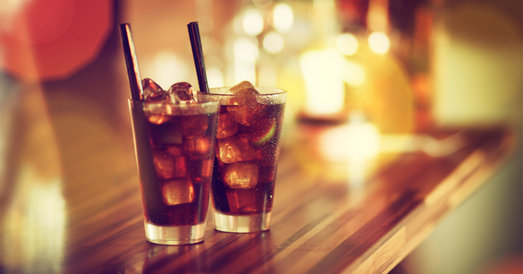 Two glasses of rum-cola cocktail with ice served on the bar